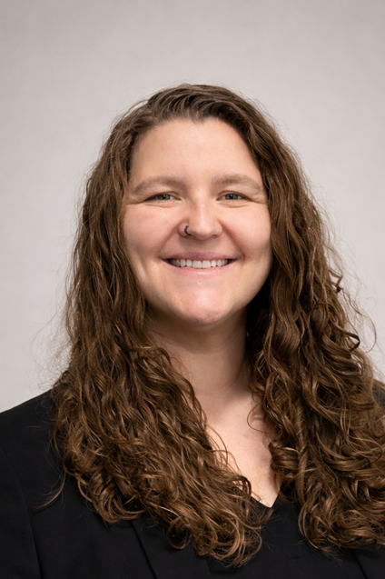 Headshot of Trisha Danah, LGBTQ+ Commissioner, smiling in a black shirt.